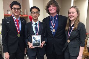 The CX Debate Team displays their district champions plaque. 