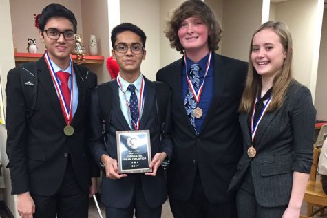 The CX Debate Team displays their district champions plaque. 
