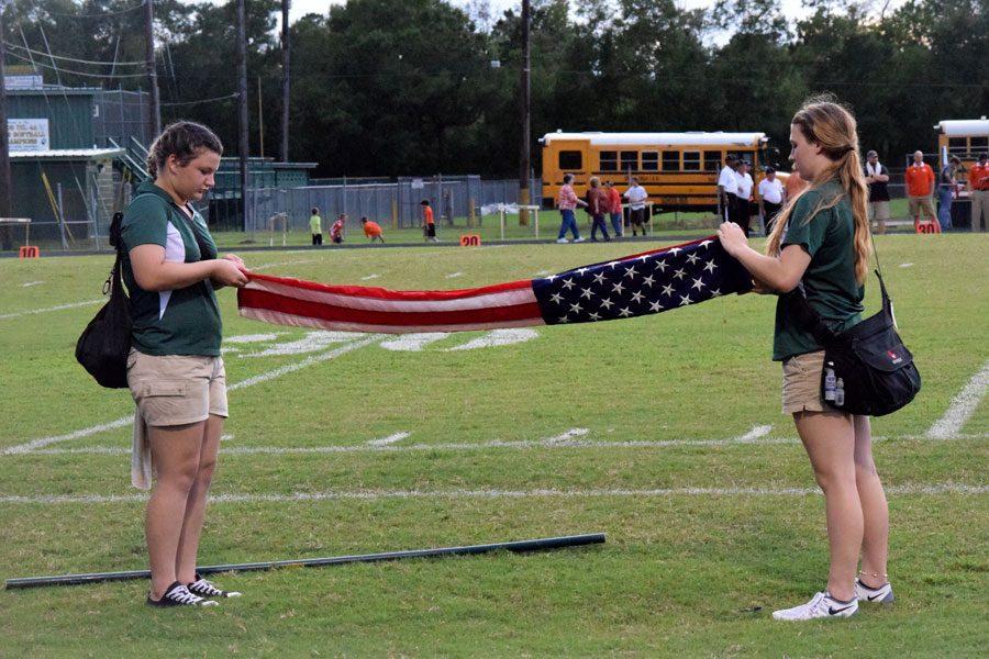 Student trainers Justice Butler and Jacie Miller concentrate on folding the flag after the national anthem. 