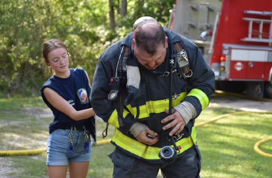 Senior Cheyenne Powell helps firefighters during a live burn practice. 